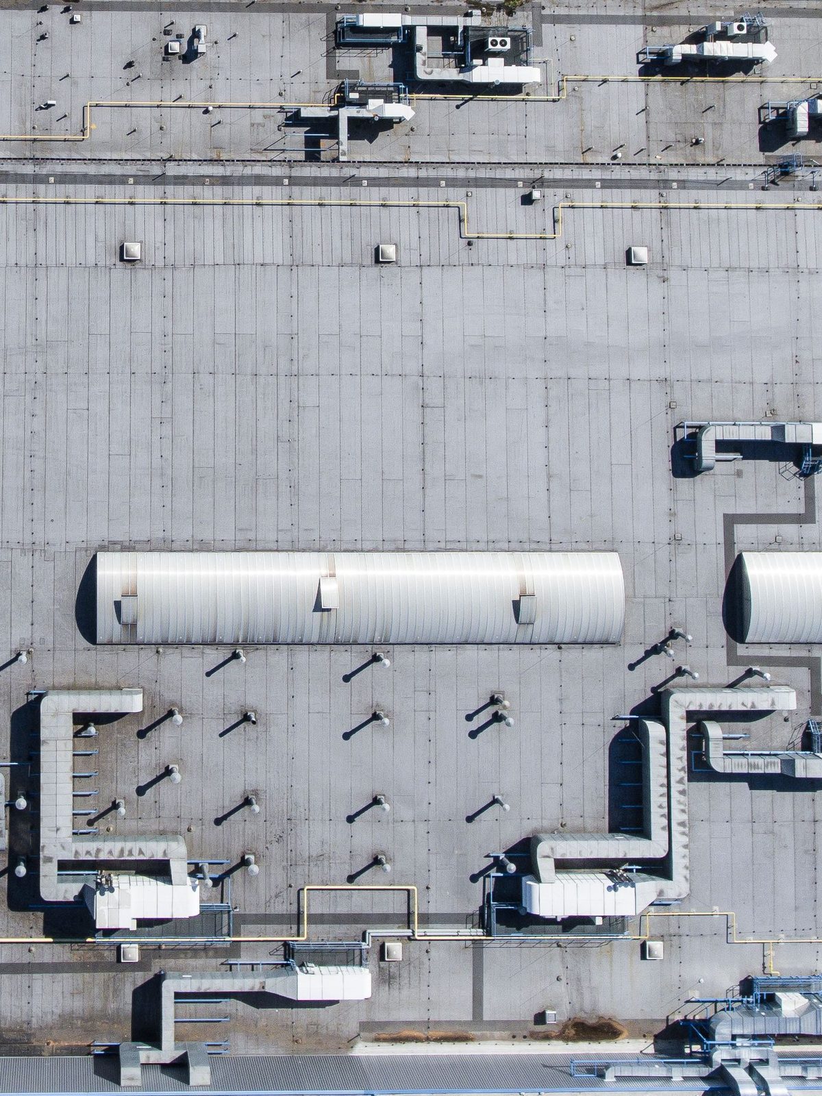 A commercial low slope roof seen from above, with ducting and rooftop units